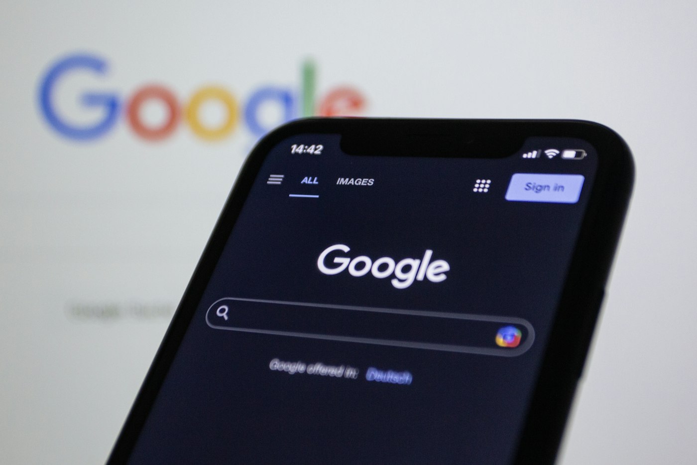 Smartphone affichant la page d’accueil de Google devant le logo Google