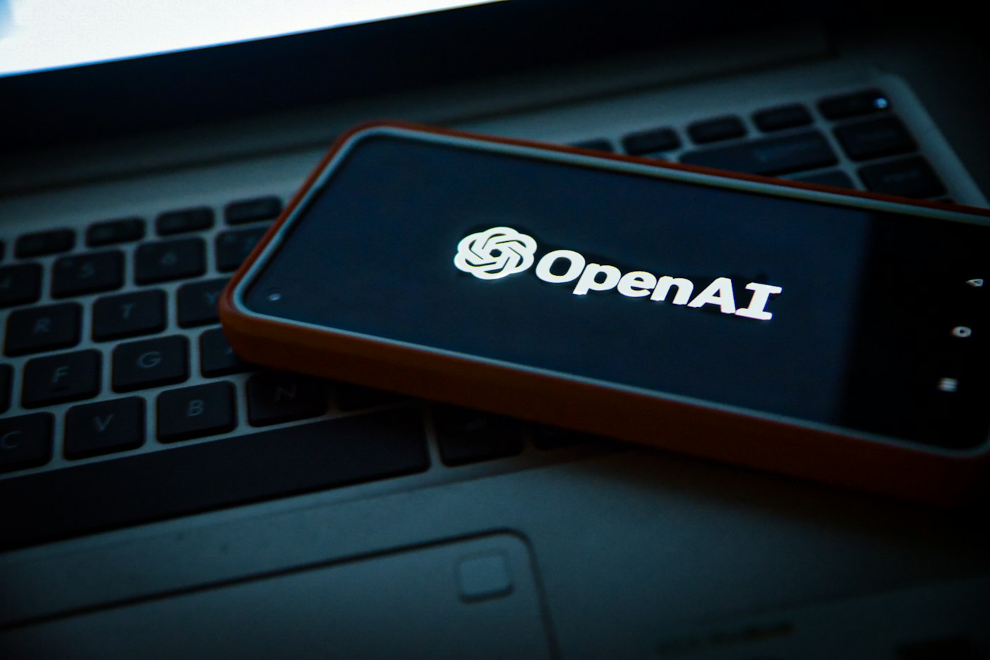 Smartphone affichant OpenAI posé sur un ordinateur portable
