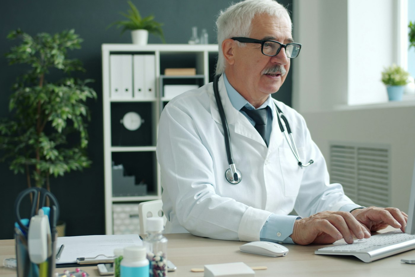 Un médecin tape sur le clavier d’un ordinateur dans un bureau d’hôpital